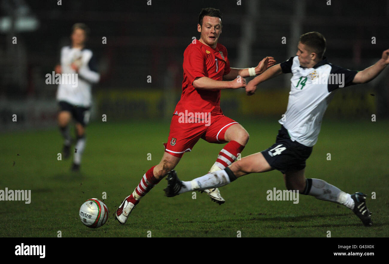 Der walisische Jake Taylor wird vom nordirischen Daniel Devine während des „Under 21 International Friendly“ auf dem Pferderennbahn-Gelände in Wrexham herausgefordert. Stockfoto