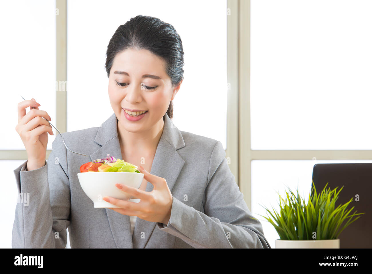 Junge asiatische Geschäftsfrau genießen einen gesunden Salat im Büro Stockfoto
