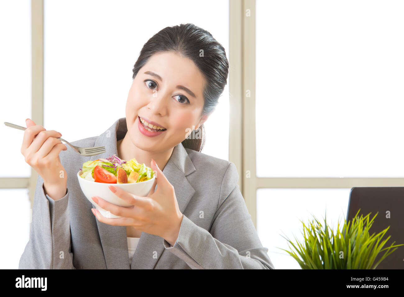 Junge asiatische Geschäftsfrau genießen einen gesunden Salat im Büro Stockfoto