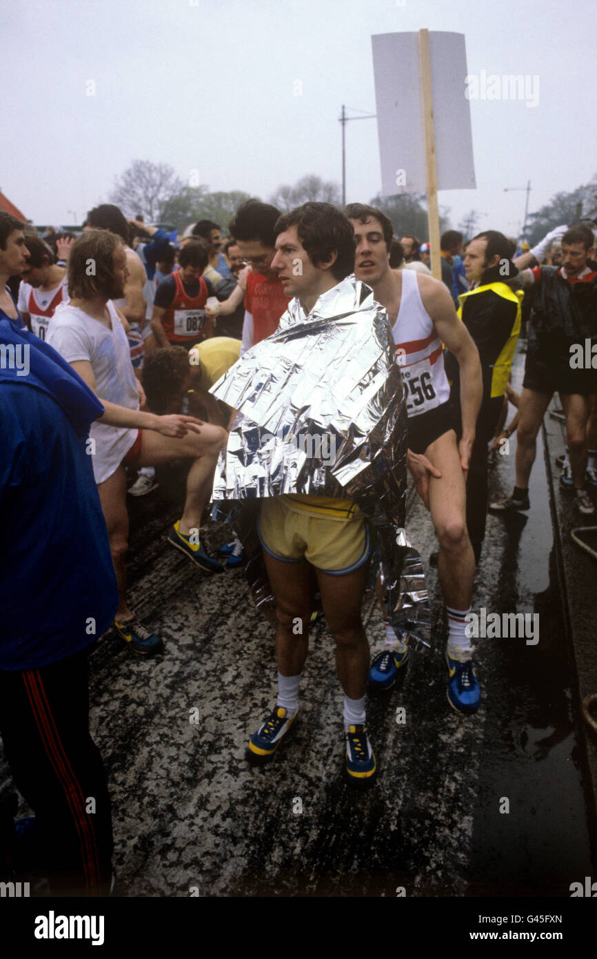 Die Teilnehmer halten sich warm und trocken, während sie den Star des ersten London-Marathons in Greenwich erwarten. Ein Teilnehmer trägt eine „Pace Blanket“ aus Aluminiumfolie, um sich warm zu halten, bevor er das 26 Meilen lange 385-Meter-Rennen bestiegen wird. Stockfoto