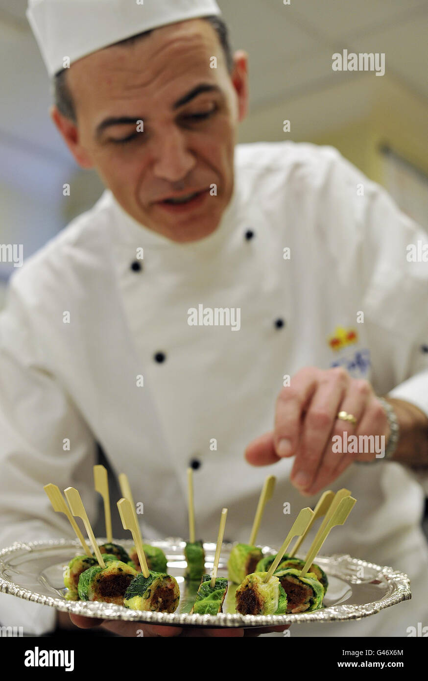 Der Chefkoch Mark Flanagan, Chef der Küche im Buckingham Palace, arrangiert ein Tablett mit Bubble und Squeak Confit mit Lammkanapees, Speisen, die dem ähneln, das normalerweise bei Empfängen im Palast serviert wird. Stockfoto