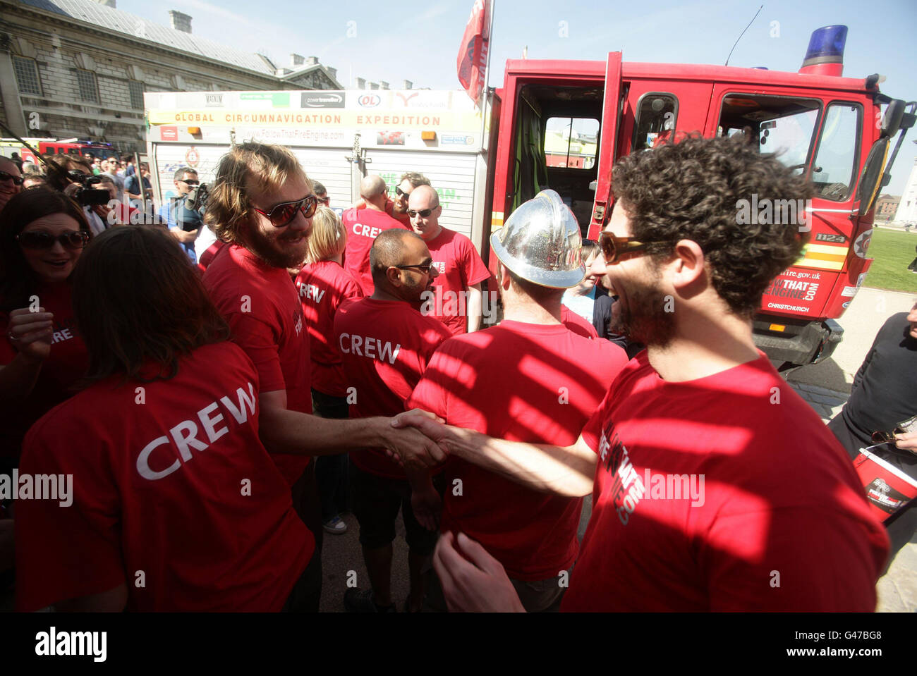 Expeditionsleiter Steve Moore (links, mit Sonnenbrille) feiert mit dem Follow That Fire Engine Team nach seiner Rückkehr in Greenwich, London, nachdem er im Juli 2010 von derselben Stelle aus abgereist war, Eine 30,000 Meilen lange Reise um die Welt im Fahrzeug zu absolvieren, um Geld für drei Wohltätigkeitsorganisationen zu sammeln - die Fire Fighters Charity, Macmillan Cancer Support und die Roy Castle Lung Cancer Foundation. Stockfoto