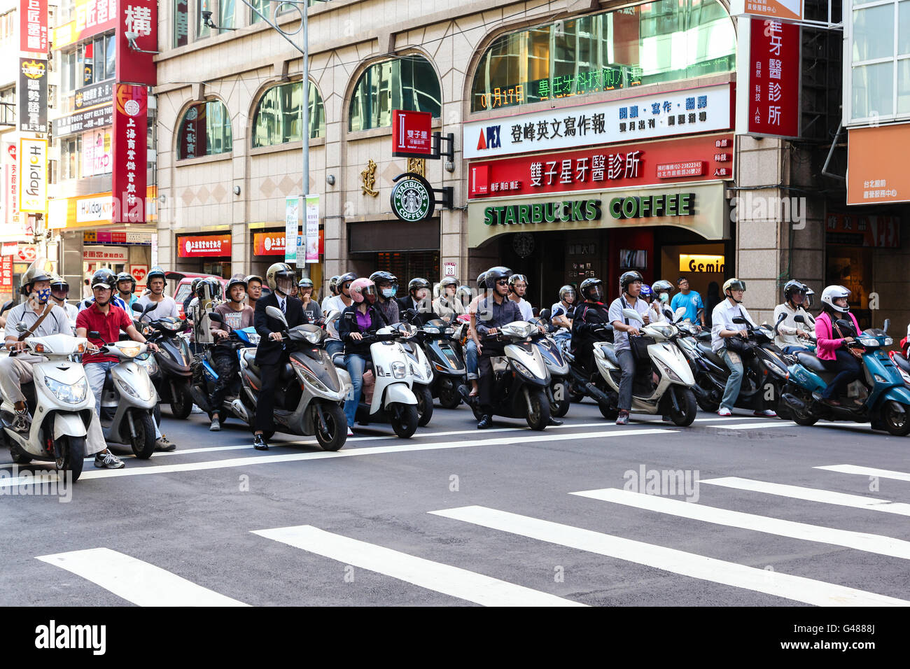 Taipeh, Taiwan: 16. Juli 2013: Rollerfahrer stoppen an einem Verkehrsknotenpunkt in Taipei City. Motorroller sind die populärste Form des Stockfoto