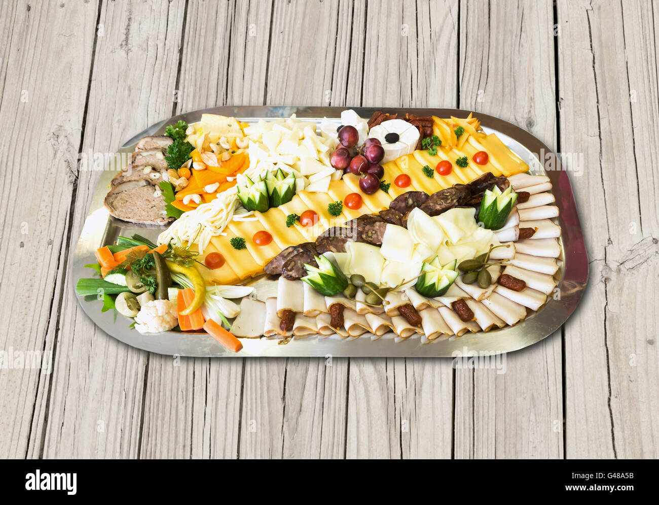 Kalte Platte mit Schinken, Käse, Oliven, Wurst, frisches Obst und Gemüse auf Holztisch Stockfoto