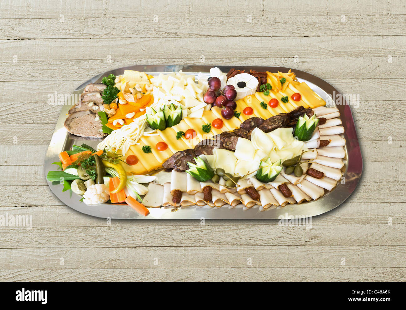 Kalte Platte mit Schinken, Käse, Oliven, Wurst, frisches Obst und Gemüse auf Holztisch Stockfoto