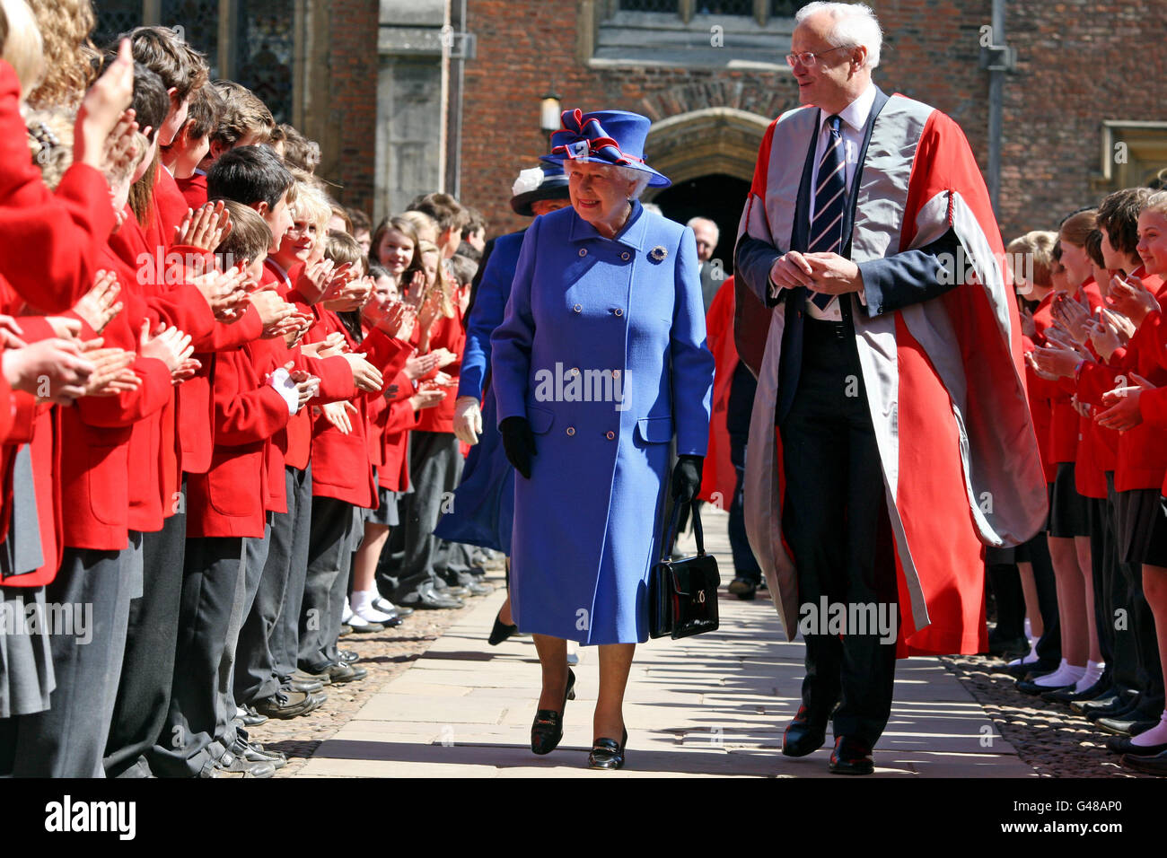 Die britische Königin Elizabeth II. Wird zusammen mit Professor Christopher Dobson von Kindern am St. John's College bei einem Besuch der Universität Cambridge in der Stadt begrüßt. Stockfoto