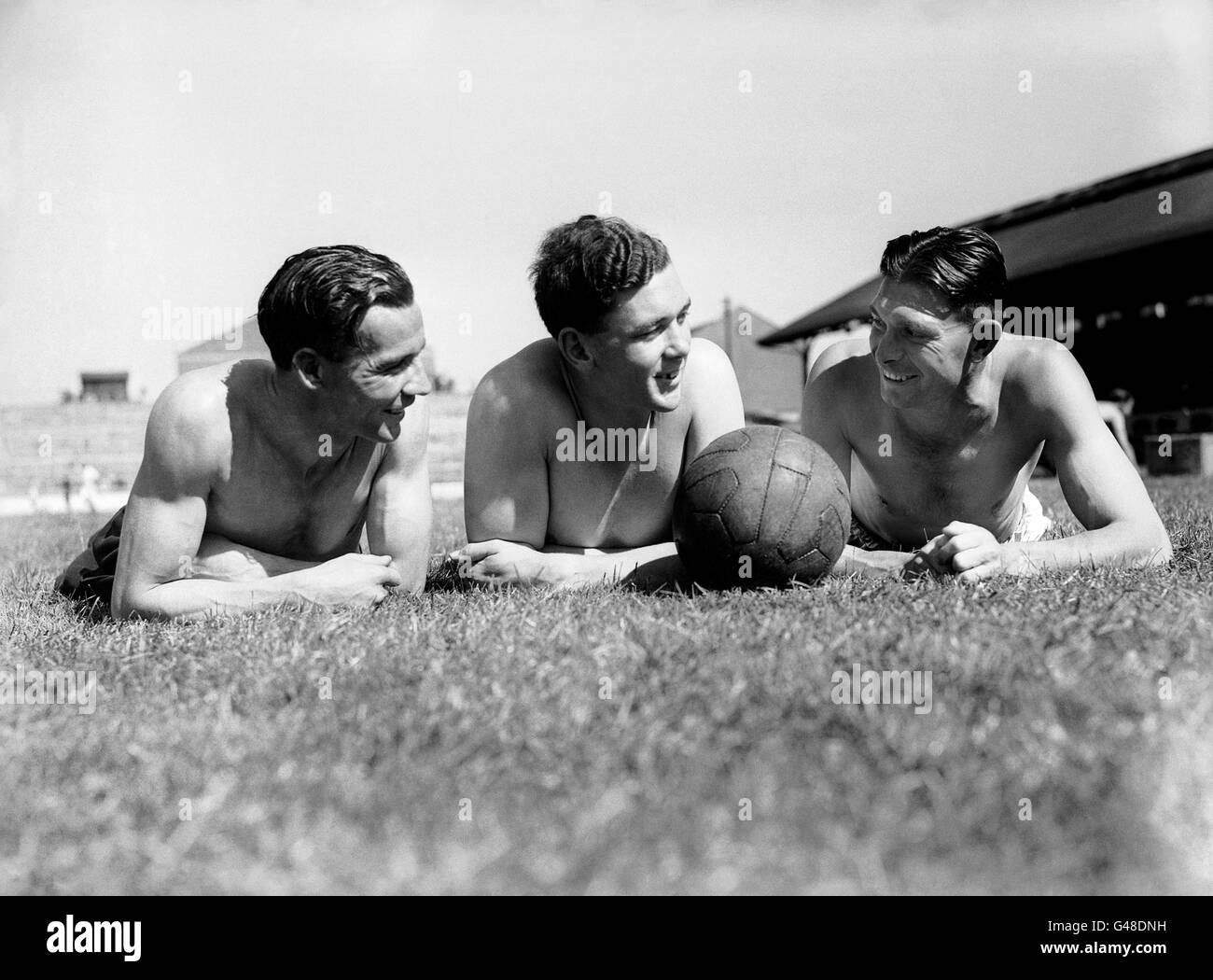 Die Fulham-Spieler (l-r) Harry Freeman, Arthur Rowley und Jim Taylor ruhen sich während des Trainings im Craven Cottage auf dem Rasen aus Stockfoto