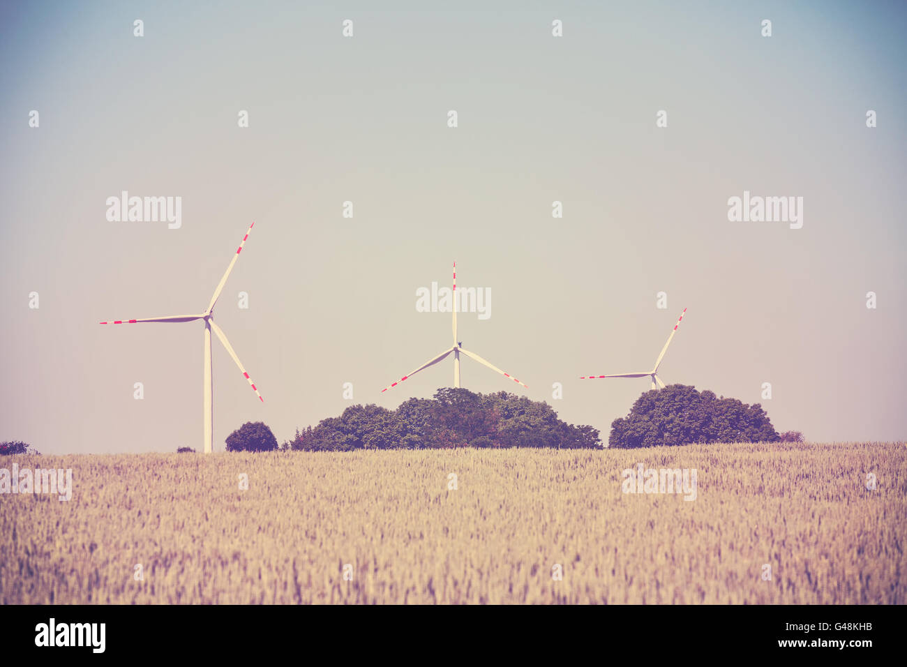 Alte Film Retro getönten Windmühlen auf einem Feld Getreide, alternative Energiekonzept. Stockfoto