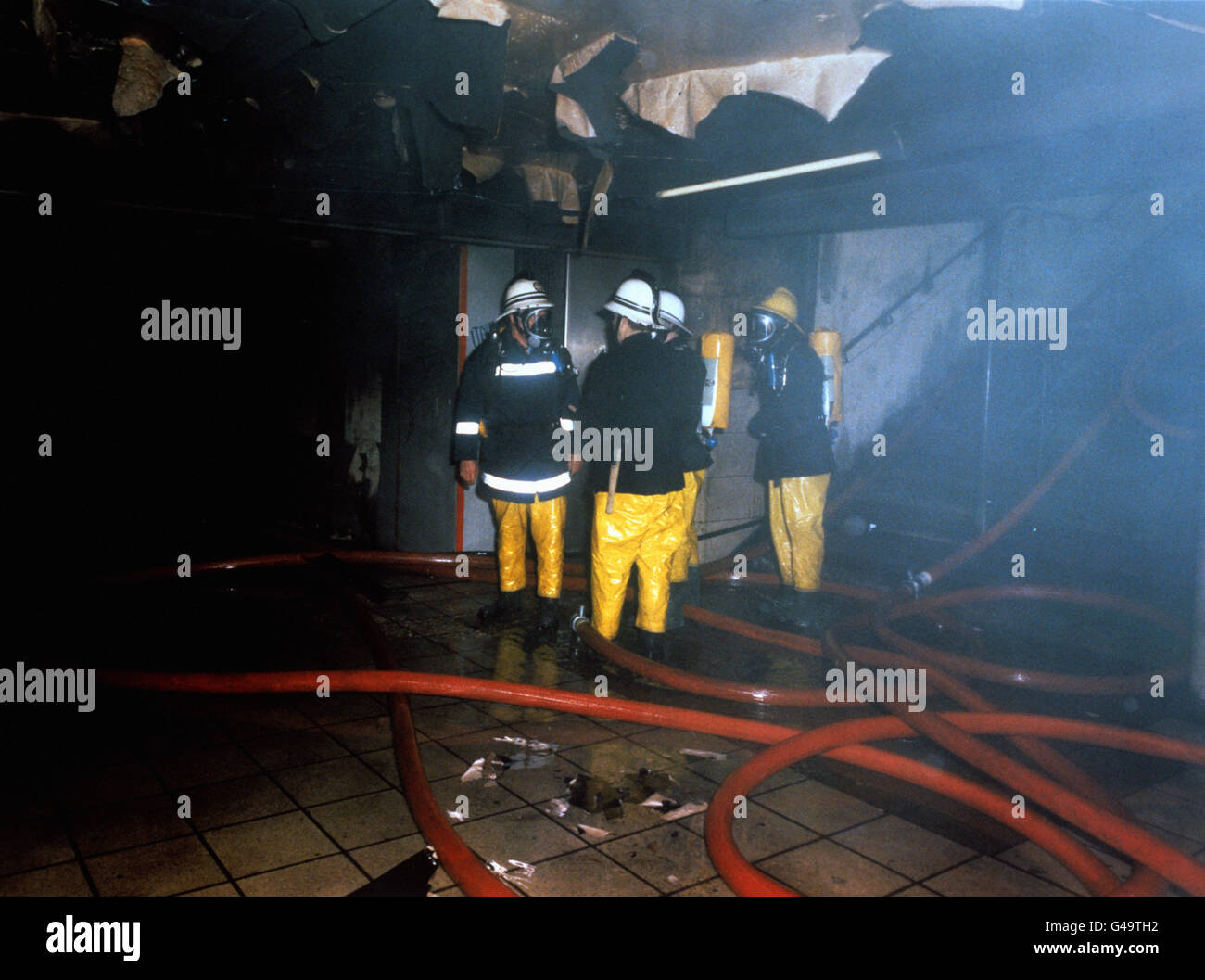 Bei einem Großbrand in Londons verkehrsreichster U-Bahnstation Kings Cross starben mindestens 31 Menschen und es wurden zahlreiche Verletzte verübt. Feuerwehrleute sind hier in den schwelenden Überresten der Hauptkartenhalle im Bahnhof zu sehen. Stockfoto