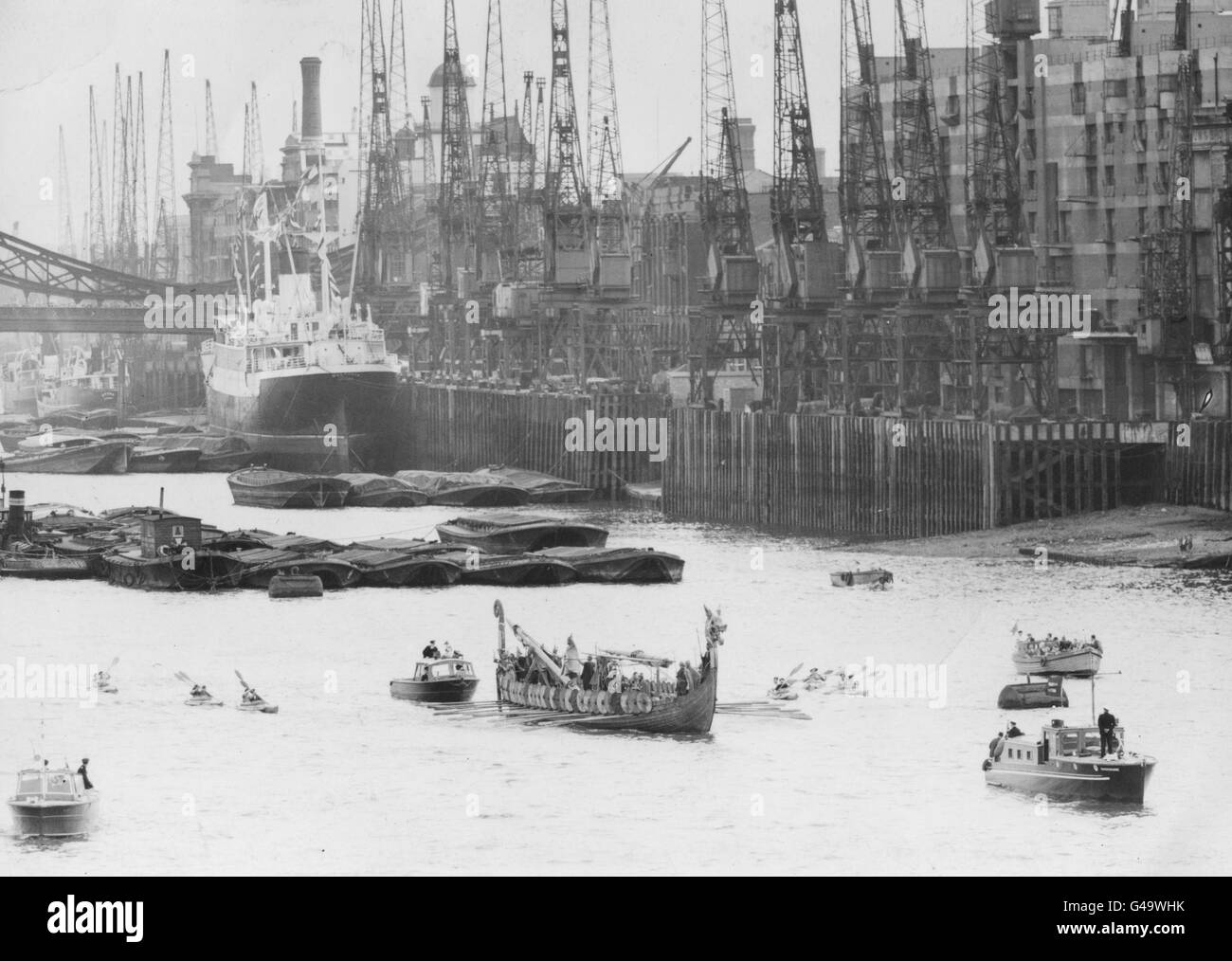 Die Kräne von Londons Uferpromenade über der Tower Bridge bilden eine Kulisse für das Wikinger-Langschiff „Hugin“ aus dem Jahr 1949, während seine Besatzung von Wikingerkriegern vom Tower Pier nach Richmond in Surrey ruht. Stockfoto