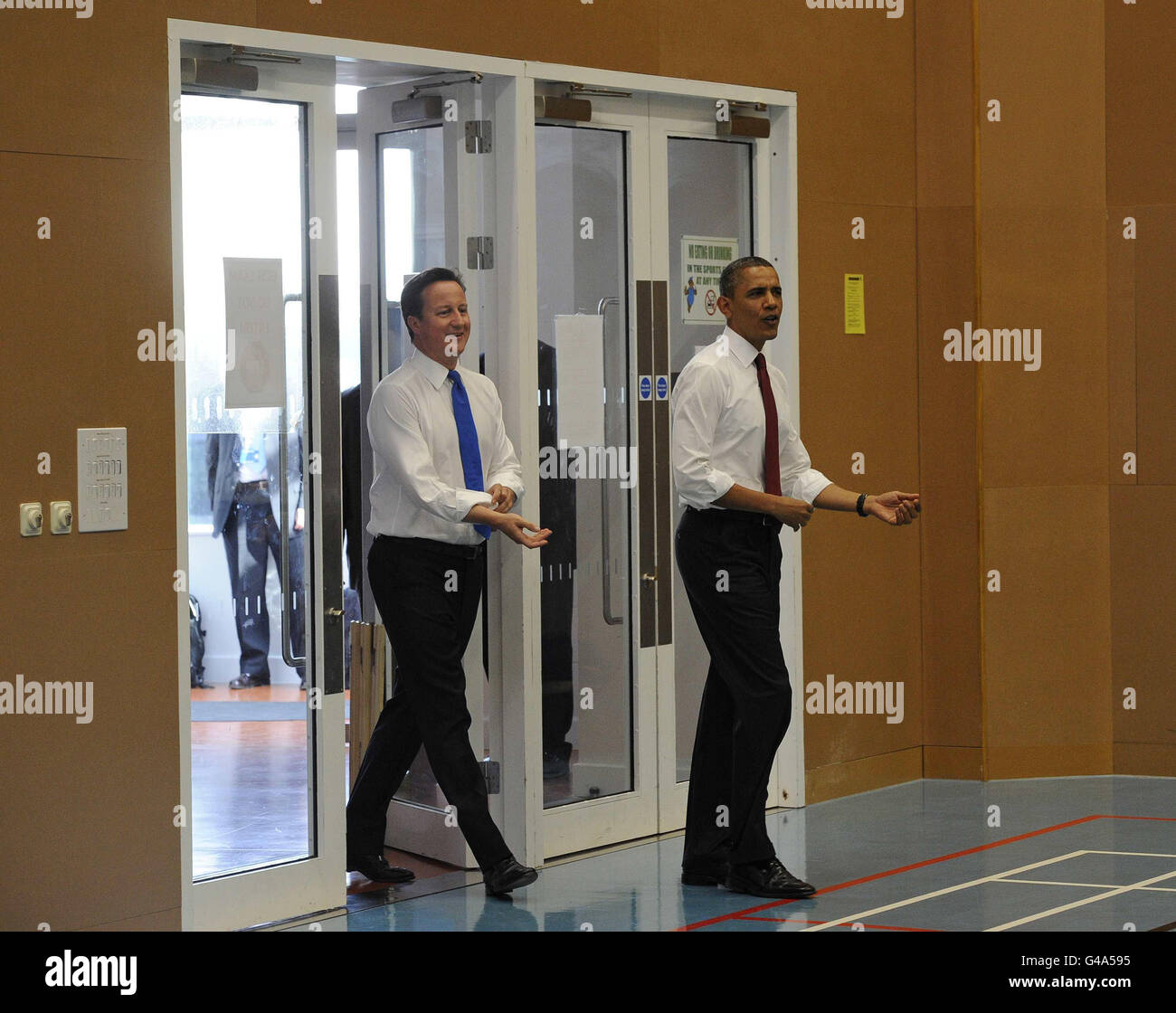Der US-Präsident Barack Obama und der britische Premierminister David Cameron Rollen ihre Hemdärmel hoch, als sie in das Gymnasium gehen, um in der Globe Academy im Süden Londons Tischtennis zu spielen, während der Präsident zu einem dreitägigen Staatsbesuch in Großbritannien aufbricht. Stockfoto