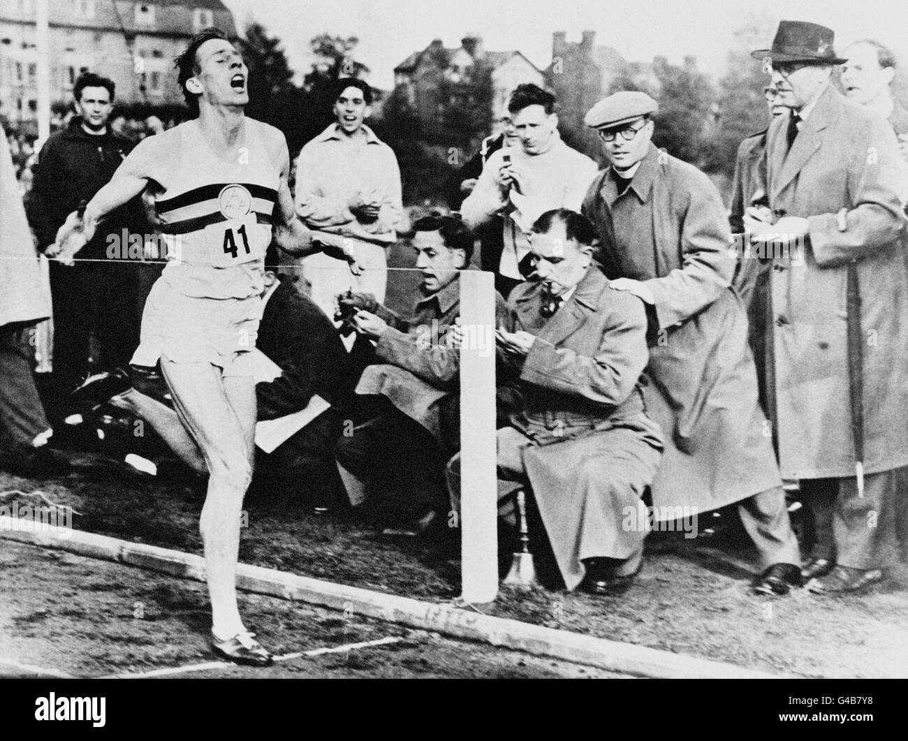 DER 25-JÄHRIGE MEDIZINSTUDENT ROGER BANNISTER TRIFFT BEI EINEM ATHLETICS MEETING IN OXFORD AUF DAS BAND, UND DIE ERSTE VIER-MINUTEN-MEILE DER WELT IST GELAUFEN. TROTZ 15 MPH WINDBÖEN, DIE AUF 25 MPH ZUSTOSSEN. BANISTER BEENDETE DIE STRECKE IN 3 MINUTEN UND 59.4 SEKUNDEN. Stockfoto