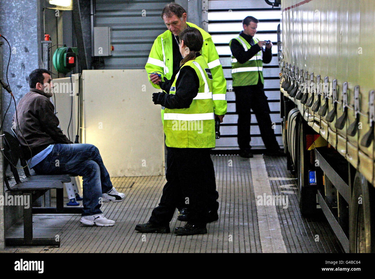 Ein verstauter Passagier in der Obhut der britischen Grenzkontrolle, nachdem er entdeckt wurde, dass er sich hinter Kisten auf der Rückseite eines LKW-Anhängers im Fährhafen von Calais in Frankreich versteckt. Stockfoto