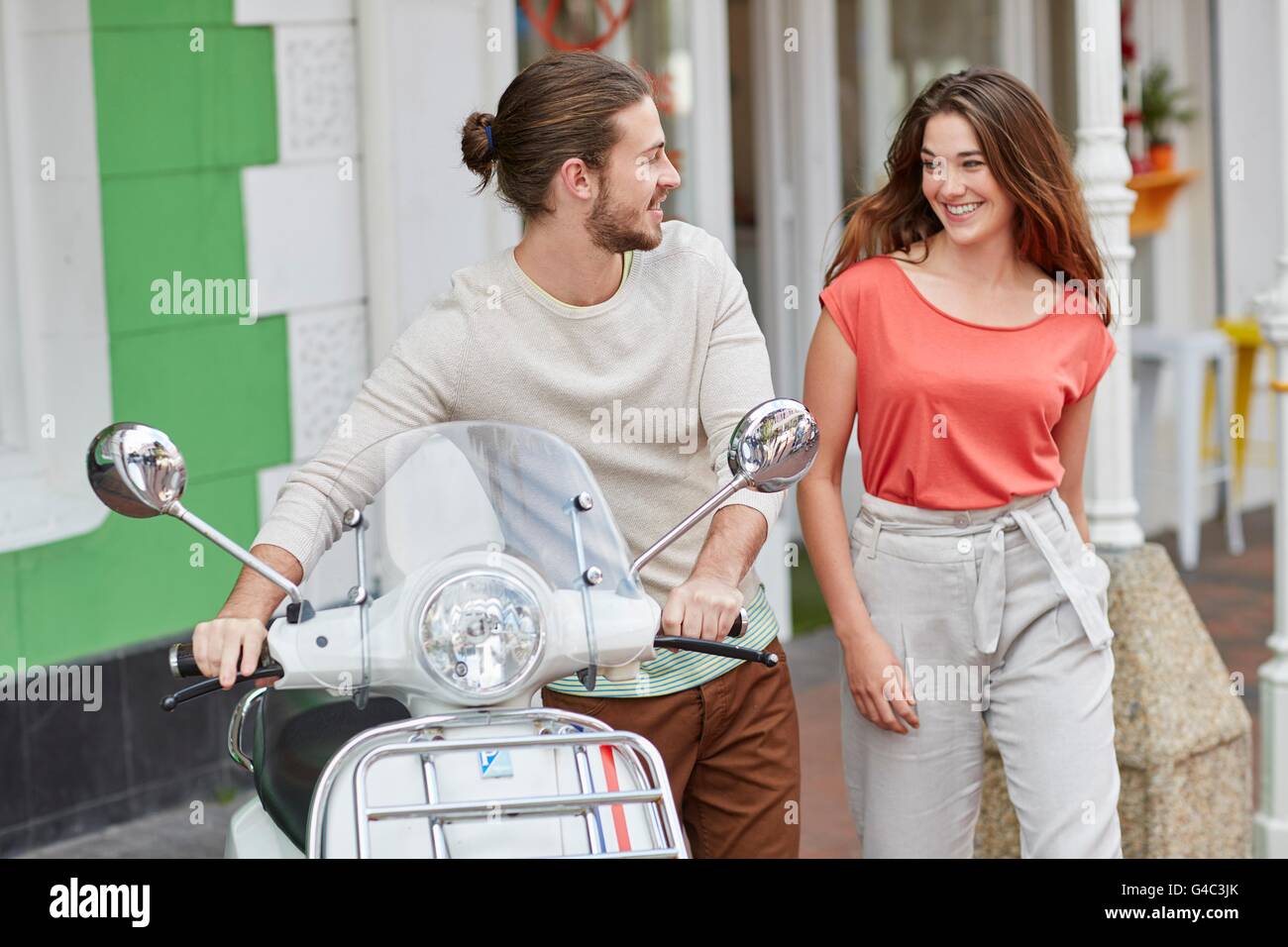 -MODELL VERÖFFENTLICHT. Junges Paar vor Café, moped Mann hält. Stockfoto