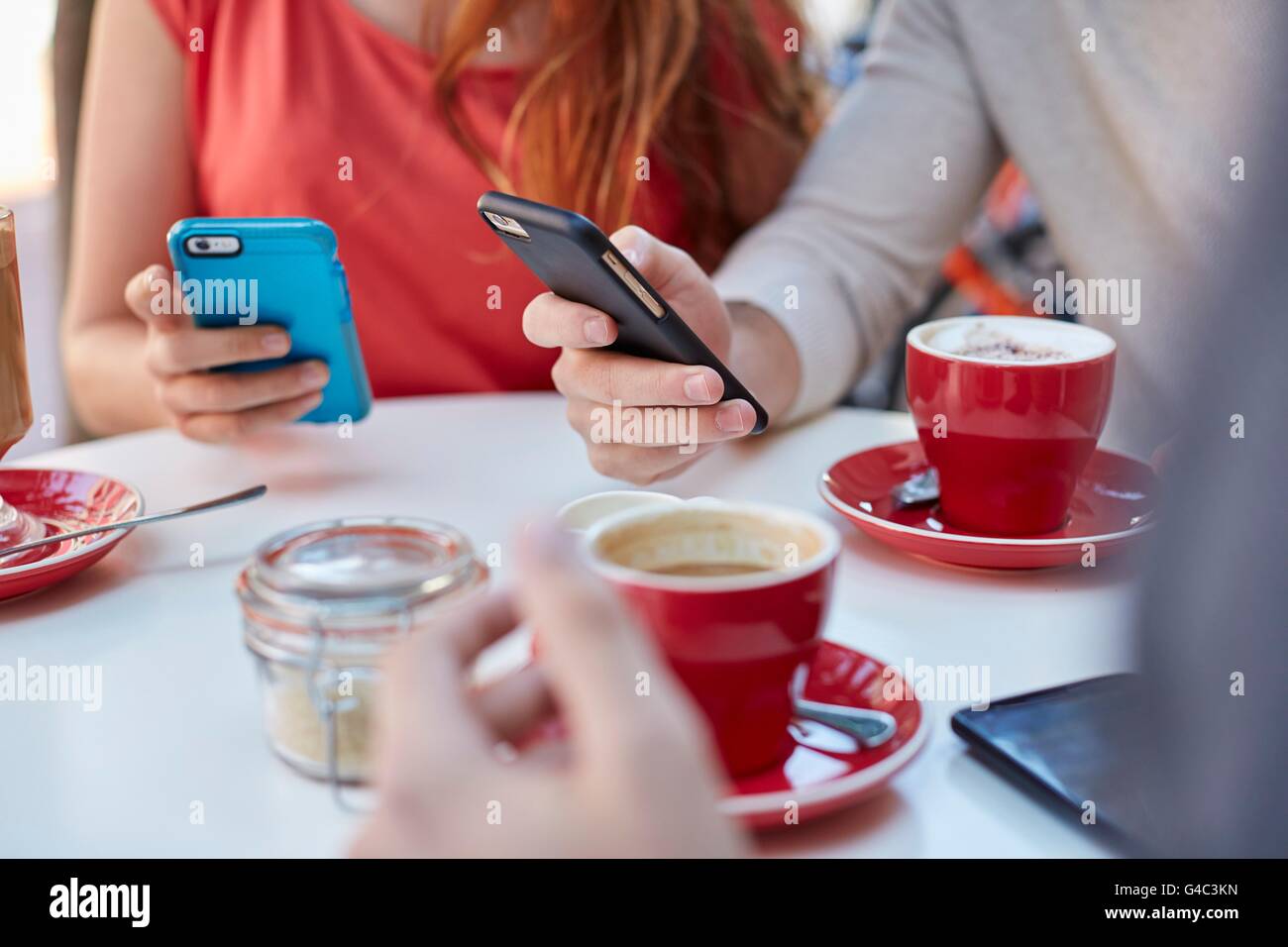 -MODELL VERÖFFENTLICHT. Junge Menschen im Café mit Smartphones. Stockfoto