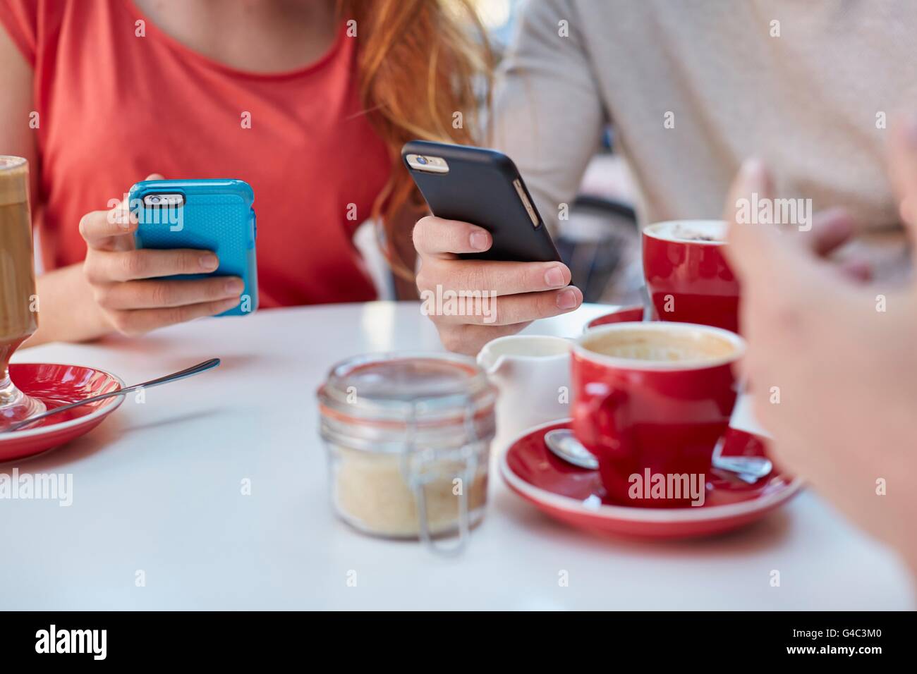 -MODELL VERÖFFENTLICHT. Junge Menschen im Café mit Smartphones. Stockfoto