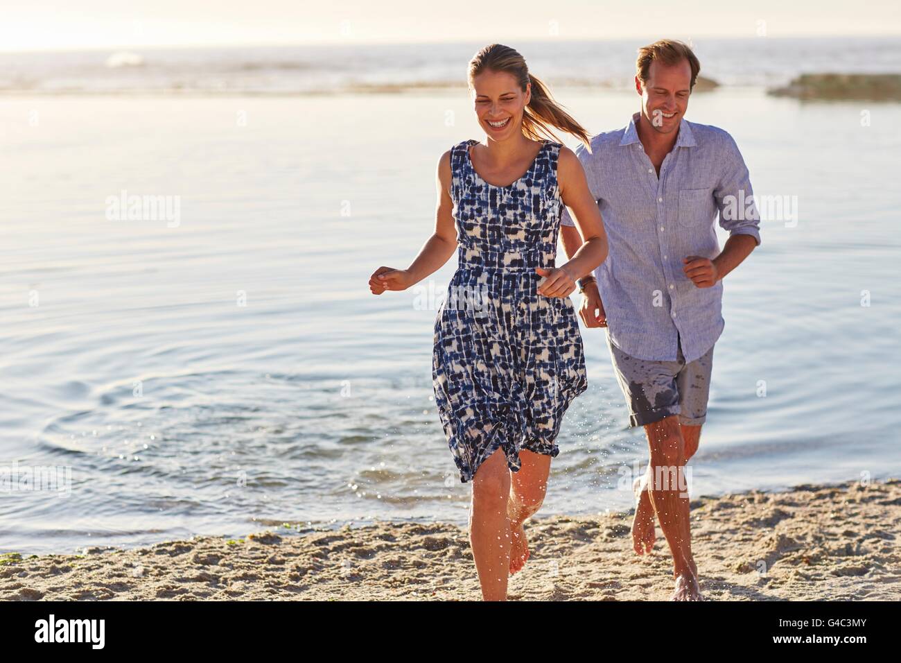 -MODELL VERÖFFENTLICHT. Paar auf an den Strand laufen Lächeln auf den Lippen. Stockfoto