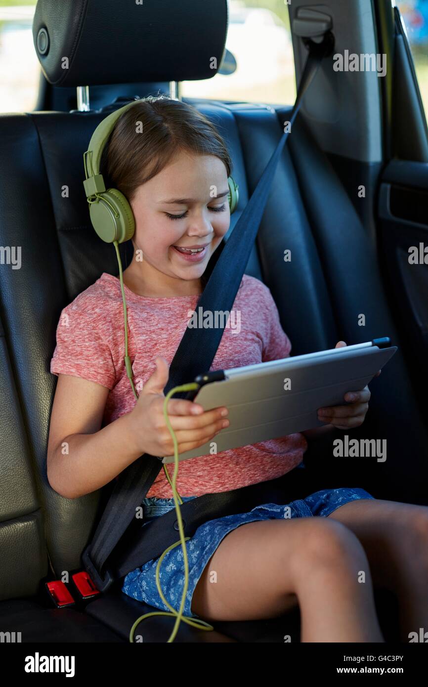 -MODELL VERÖFFENTLICHT. Mädchen auf dem Rücksitz des Autos tragen von Kopfhörern, einen Film. Stockfoto