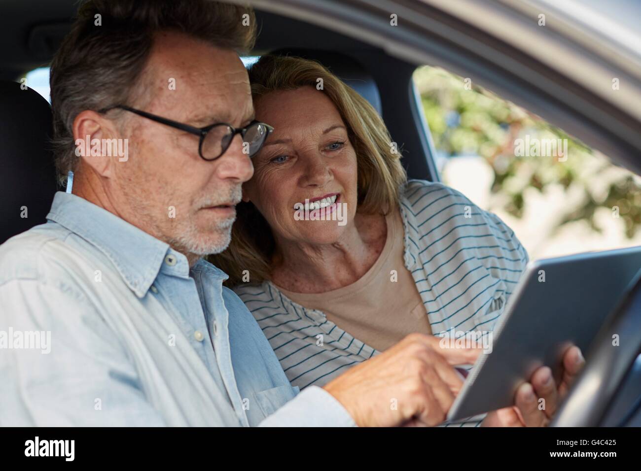 -MODELL VERÖFFENTLICHT. Älteres Paar im Auto mit einem digital-Tablette. Stockfoto