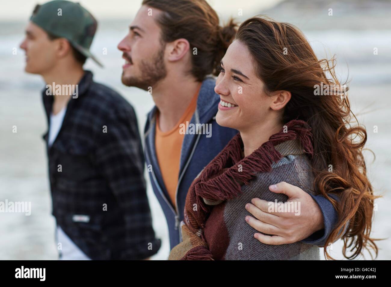 -MODELL VERÖFFENTLICHT. Junges Paar am Strand mit Freund. Stockfoto