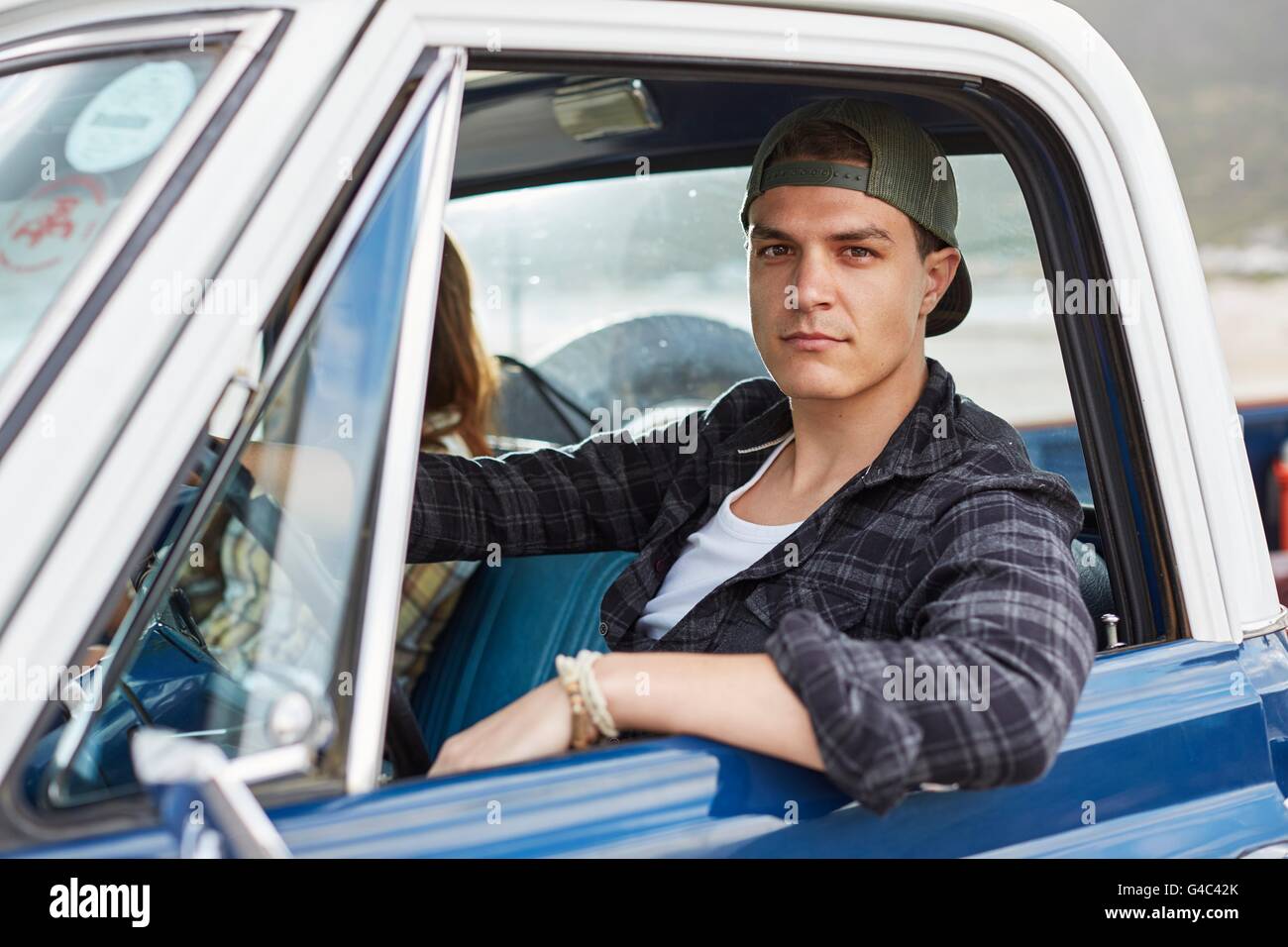 -MODELL VERÖFFENTLICHT. Junger Mann, Blick in die Kamera durch offenen Autofenster. Stockfoto