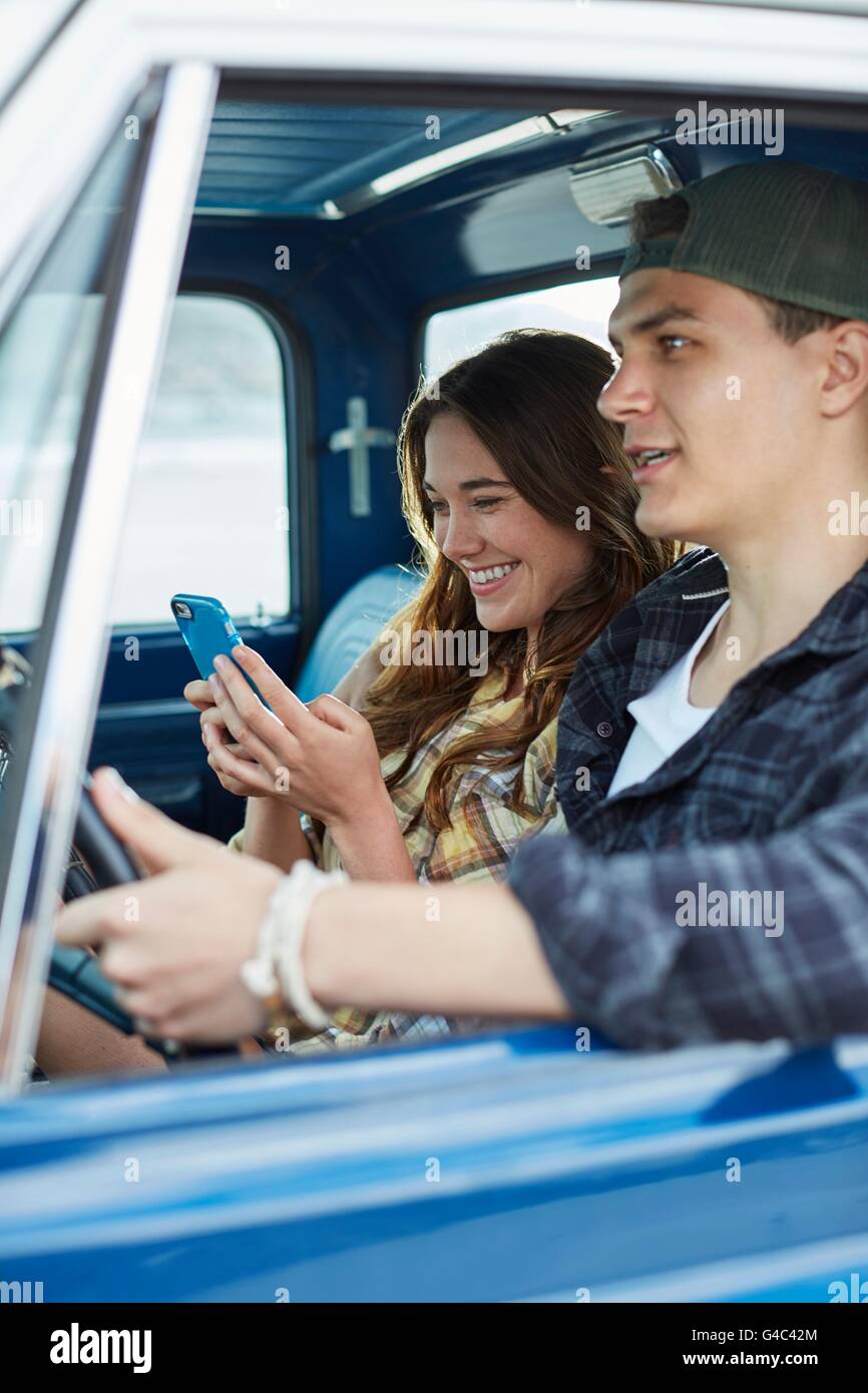 -MODELL VERÖFFENTLICHT. Junges Paar in einem Auto, Frau mit Smartphone. Stockfoto