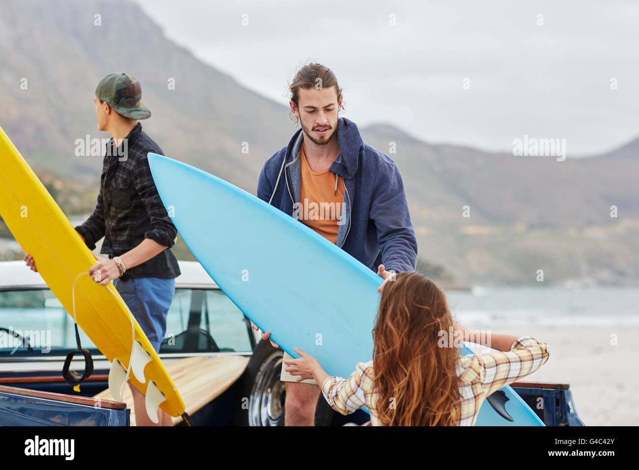 -MODELL VERÖFFENTLICHT. Junge Frau Surfbrett Mann übergeben. Stockfoto