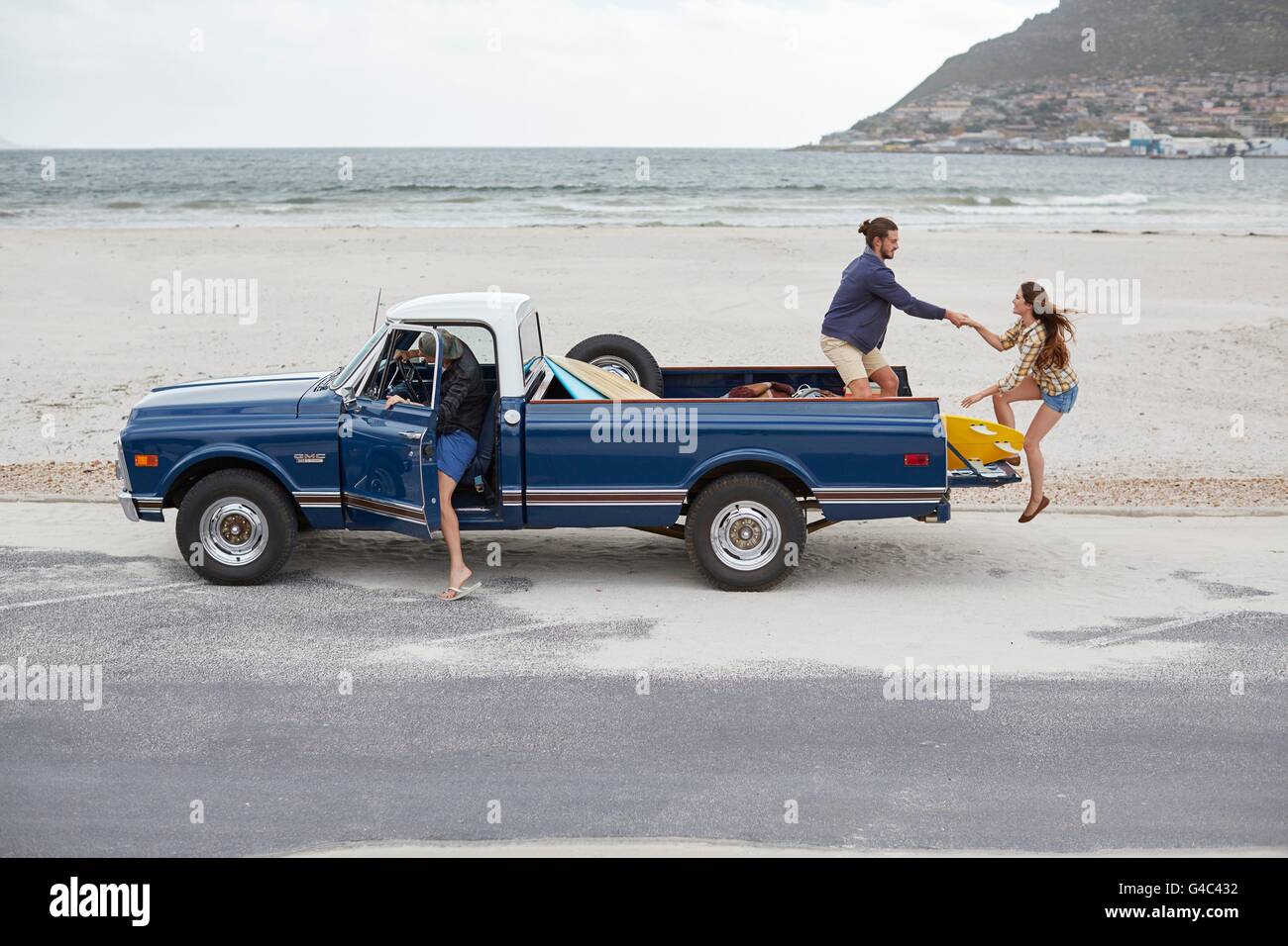 -MODELL VERÖFFENTLICHT. Junge Frau geholfen sich in Pick-up LKW am Strand. Stockfoto