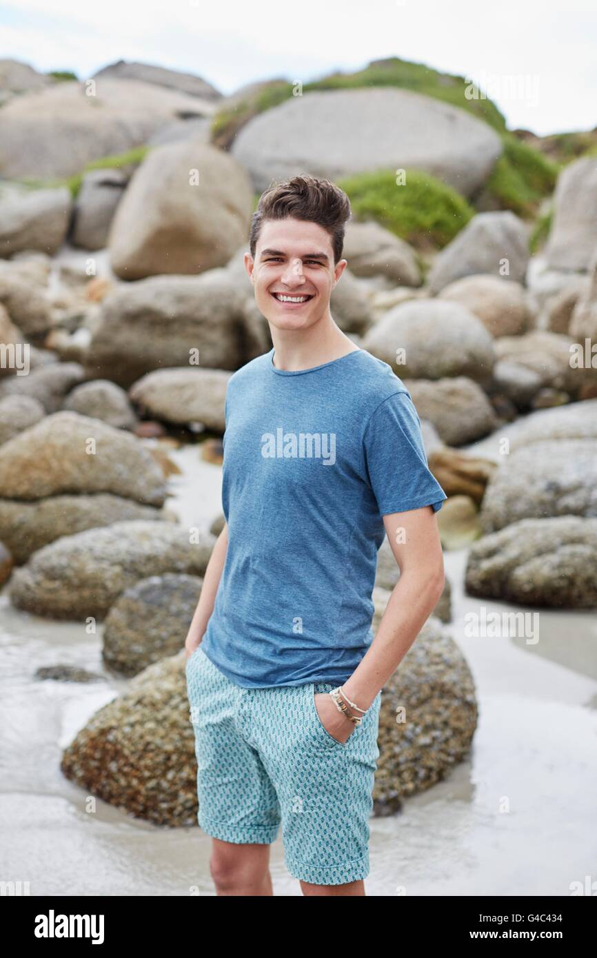-MODELL VERÖFFENTLICHT. Junger Mann am Strand in Richtung Kamera lächelt. Stockfoto
