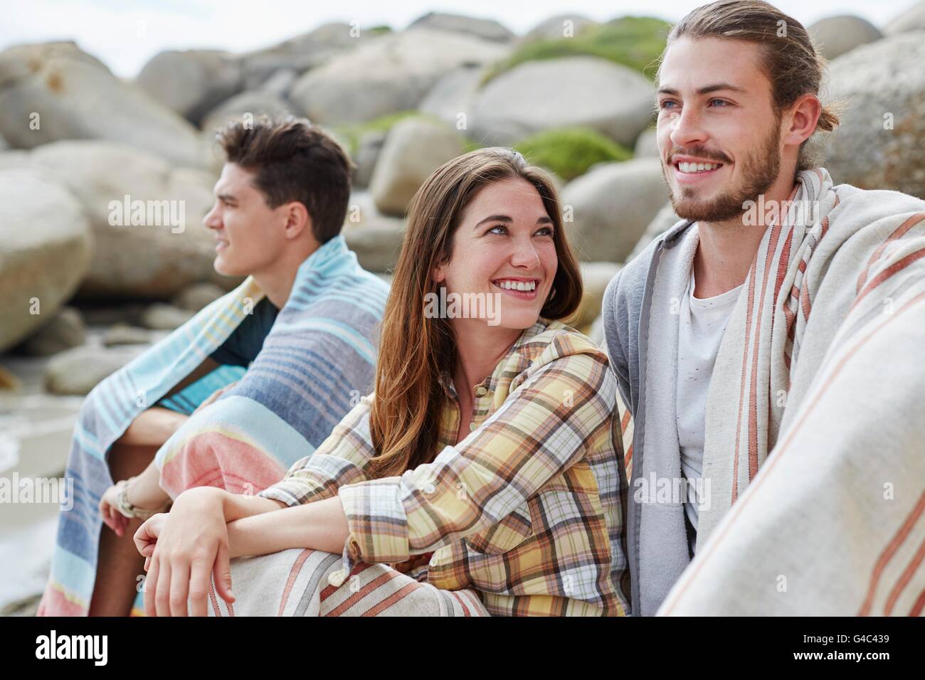 -MODELL VERÖFFENTLICHT. Junge Erwachsene am Strand in Decken gehüllt. Stockfoto