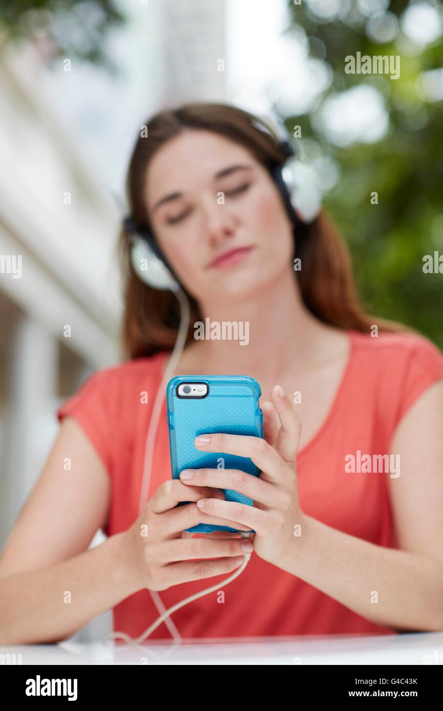 -MODELL VERÖFFENTLICHT. Junge Frau mit Kopfhörern anhören von Musik auf Smartphone. Stockfoto