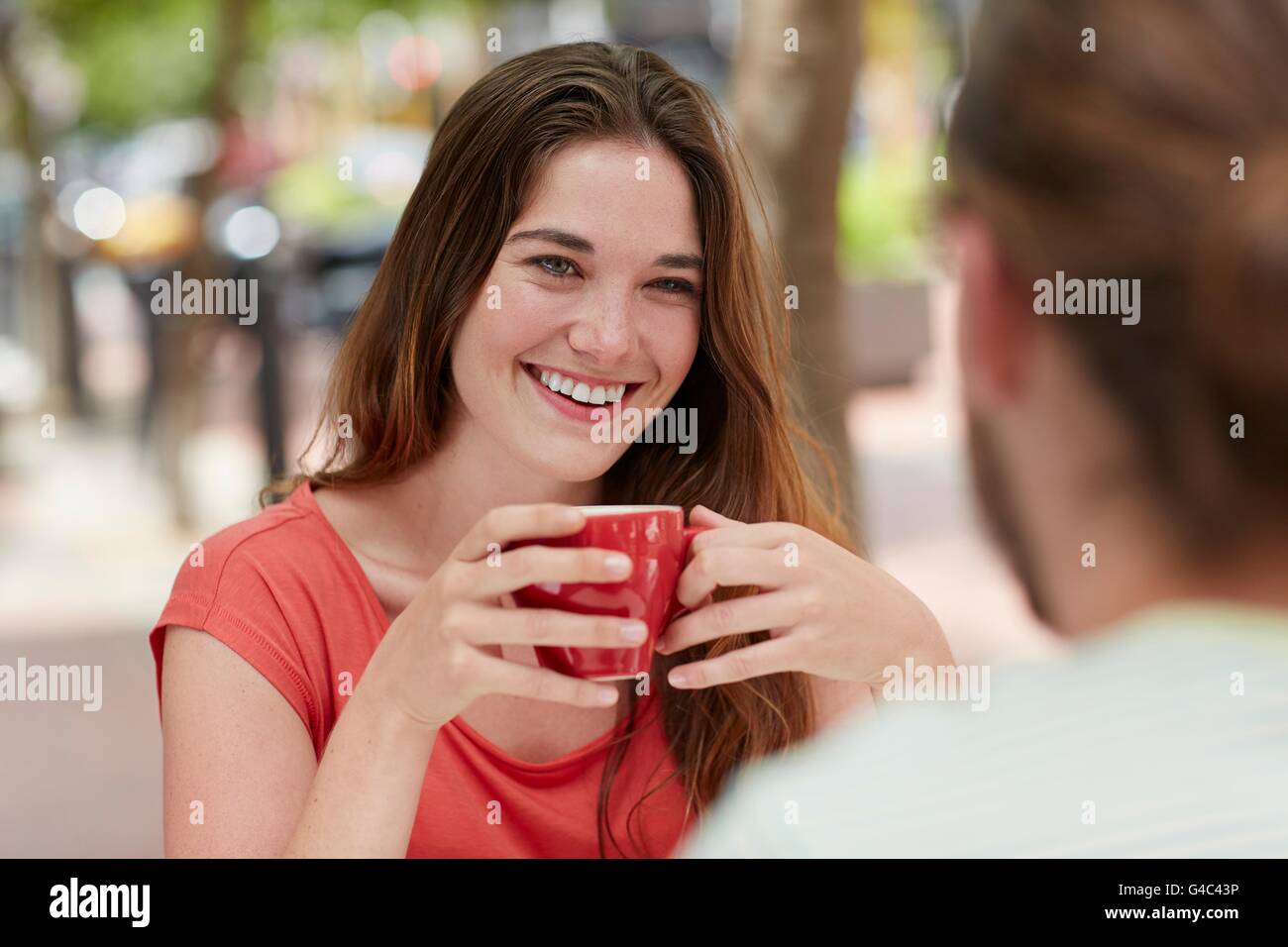 -MODELL VERÖFFENTLICHT. Junge Frau trinkt Kaffee mit Freundin. Stockfoto