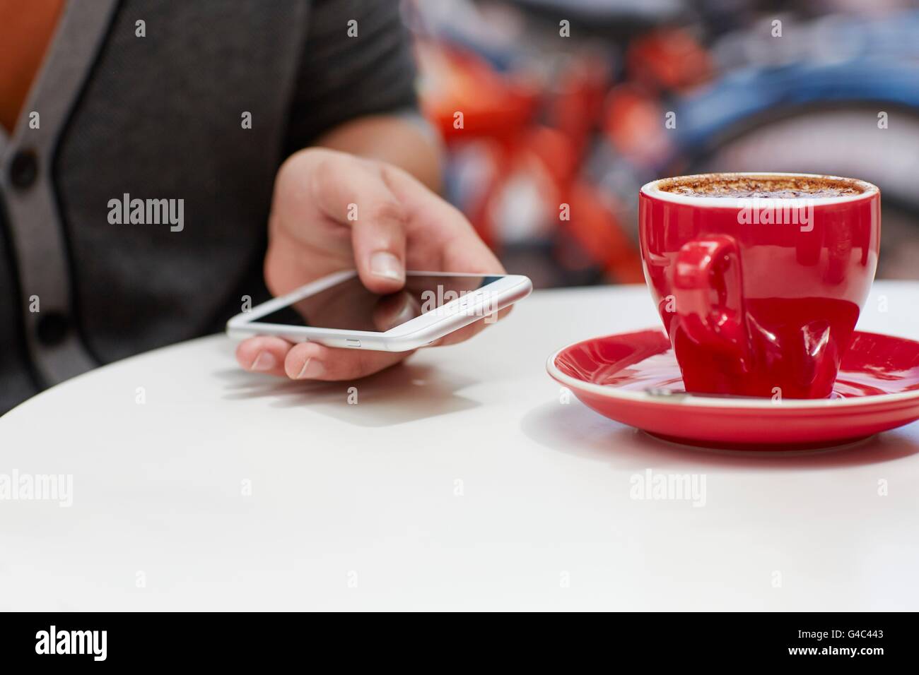 -MODELL VERÖFFENTLICHT. Person mit Smartphone mit Kaffee, Nahaufnahme. Stockfoto