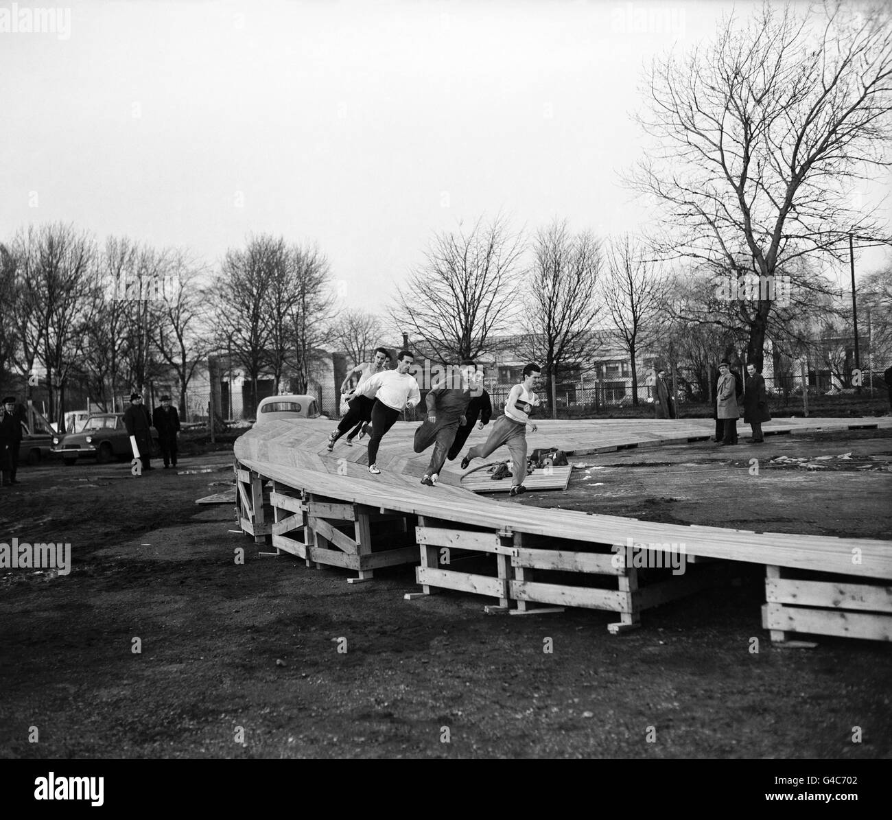 Athleten, die eine der verwachten Kurven der Indoor-Holzbahn ausprobieren, die am Empire Pool genutzt werden soll, auf einem Parkplatz in der Nähe des Wembley Stadions Stockfoto