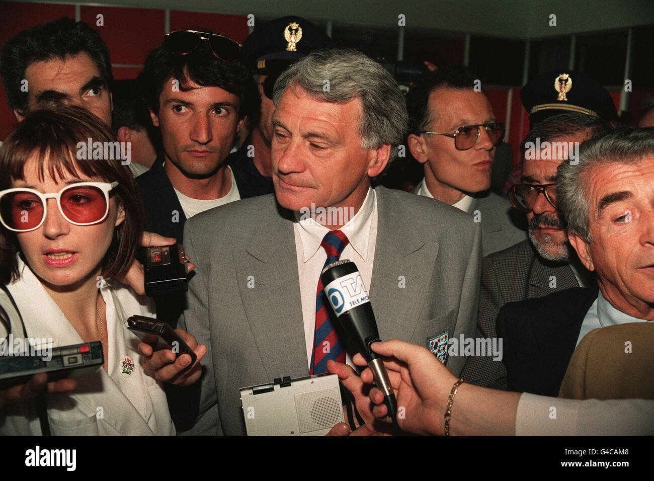 PA NEWS FOTO 25/5/90 MANAGER BOBBY ROBSON, FUSSBALLNATIONALMANNSCHAFT ENGLAND STEHT IM MITTELPUNKT DER AUFMERKSAMKEIT DER MEDIENVERTRETER WIE ER ANKUNFT MIT DEM ENGLISCHEN TEAM AM FLUGHAFEN CAGLIARI IN ITALIEN FÜR DAS WM-TURNIER Stockfoto