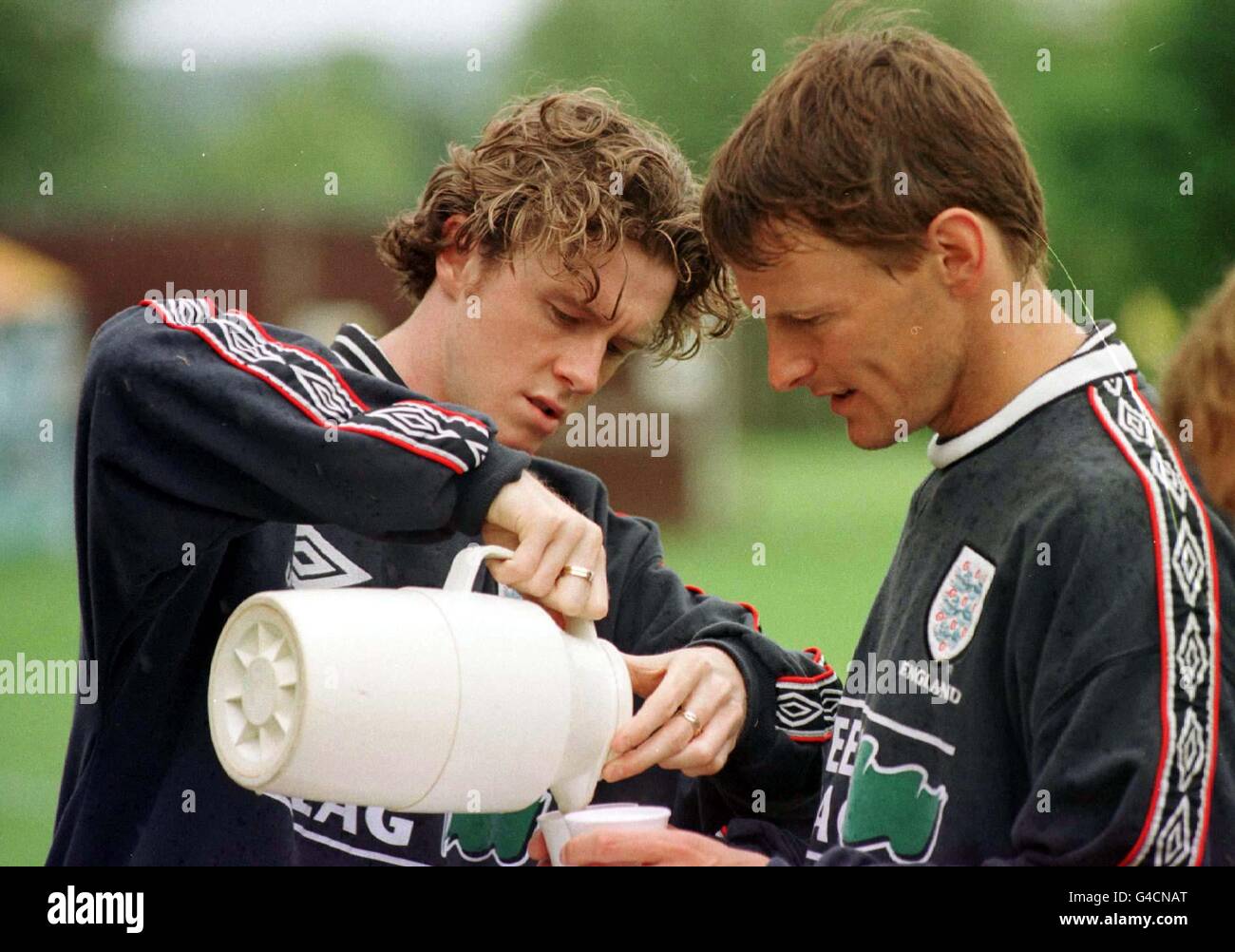 Der Engländer Steve McManaman gießt Teddy Sheringham (rechts) heute (Montag) bei einem Training in Bisham Abbey einen Drink, bevor er morgen zur Weltmeisterschaft auffährt. Foto von Adam Butler/PA. Stockfoto