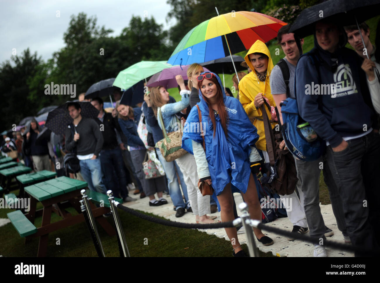 Tennisspieler schützen sich vor Regen, während sie am fünften Tag der Wimbledon Championships 2011 im All England Lawn Tennis Club, Wimbledon, Schlange stehen, um Tickets zu verkaufen. Stockfoto