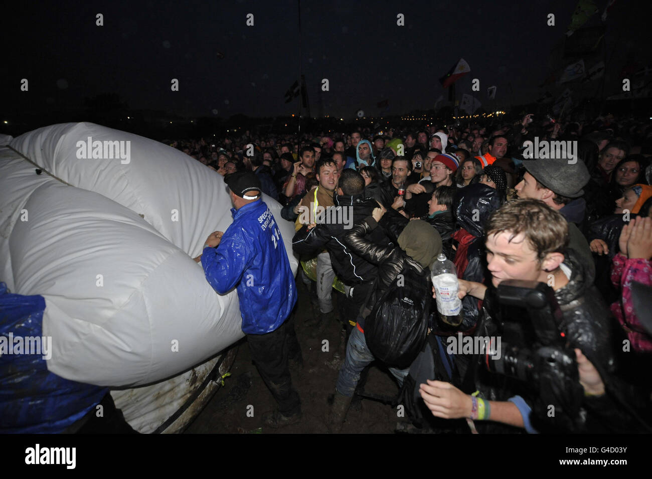 Sicherheitspersonal und Mitglieder der direkten Aktionsgruppe Art Uncut, tossle über einen 20 Fuß großen Ballon mit der Botschaft "U Pay Your Tax 2", während die Rockband U2 auf der Pyramid Stage beim Glastonbury Musikfestival in Worthy Farm, Pilton auftreten. Stockfoto