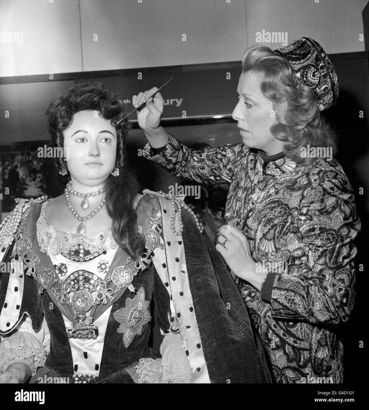 Die Schauspielerin Margaret Tyzack bearbeitet das Make-up auf dem Totenbild in Wachs von Königin Anne (die 1714 im Alter von 49 Jahren starb) im Norman Undercroft in Westminster Abbey, wo es eine Sammlung königlicher Bildnisse gibt. Margaret Tyzack, die für ihre Darbietung als Königin Anne in der Fernsehserie „The First Churchills“ einen Preis für die Schauspielerin des Jahres erhielt, wurde eingeladen, bei der Verstellung der Perücke zu helfen, die von Roger Isaia angefertigt und präsentiert wurde. Stockfoto