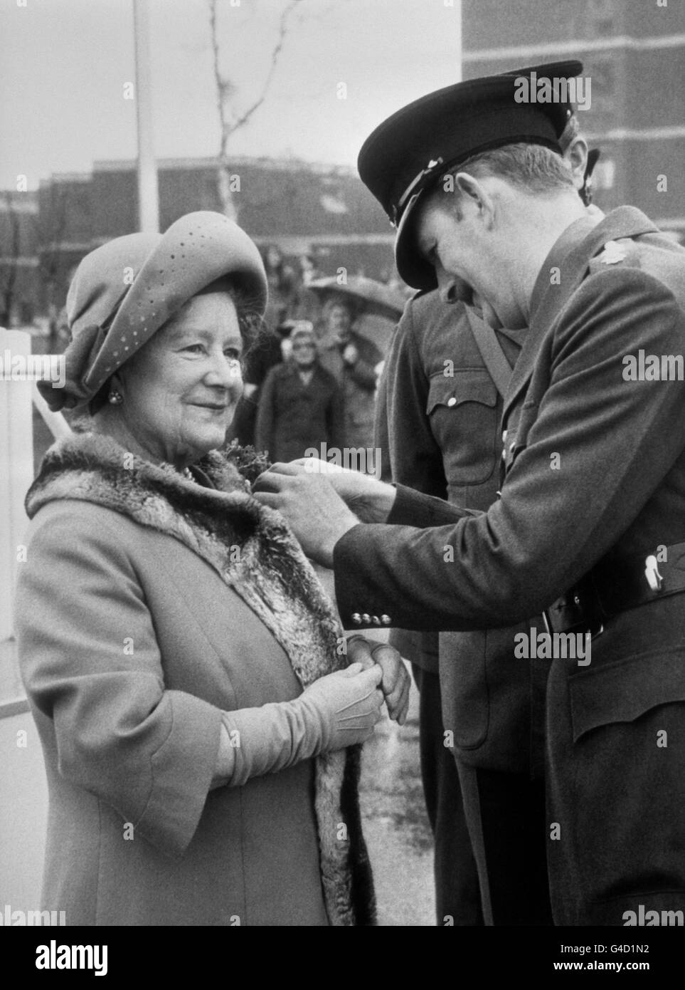 Kapitän R. Cohap überreicht der Queen Mother einen Shamrock, als sie anlässlich des St. Patrick's Day die Irish Guards Company im Guards' Depot, Pirbright, Surrey, besuchte. Die Mutter der Königin beobachtete eine Parade, bevor sie mit Beamten zu Mittag aßen. Stockfoto