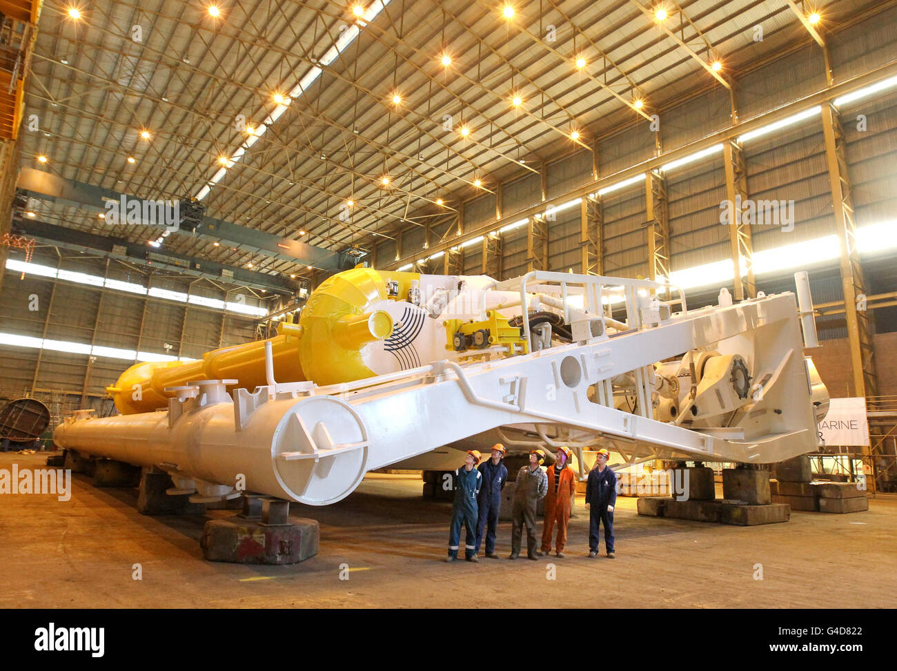 Arbeiter vor dem hydroelektrischen Gerät der nächsten Generation von Aquamarine Power mit 800 kW, wie es auf der Werft Burntisland Fabrications in Methil, Fife, vorgestellt wird. DRÜCKEN SIE VERBANDSFOTO. Bilddatum: Mittwoch, 13. Juli 2011. Die Bemühungen, kosteneffizienten Strom aus dem Meer zu erzeugen, sind mit der Einführung des neuen Wellenenergie-Geräts einen Schritt nach vorn getan. Die neue Oyster 800 kann zu einem Drittel der Kosten 250 % der Leistung des ersten Vollausbau-Oyster-Geräts erzeugen, das Ende 2009 am European Marine Energy Center (EMEC) in Orkney installiert und ans Stromnetz angeschlossen wurde. Siehe PA-Geschichte SCOTLAND Energy. Foto Stockfoto