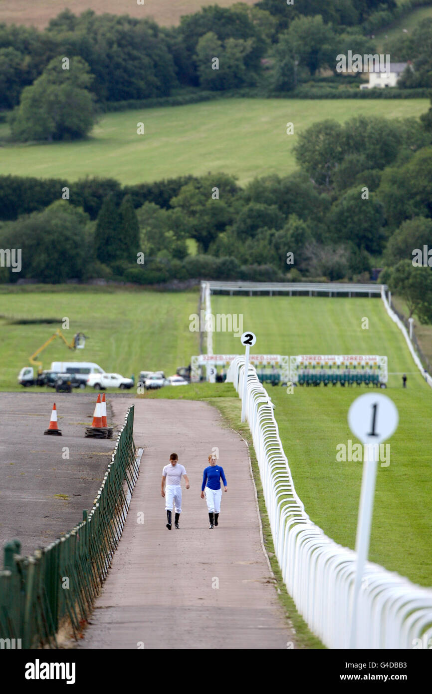 Zwei Jockeys laufen neben einem leeren Platz auf der Rennbahn Chepstow Stockfoto