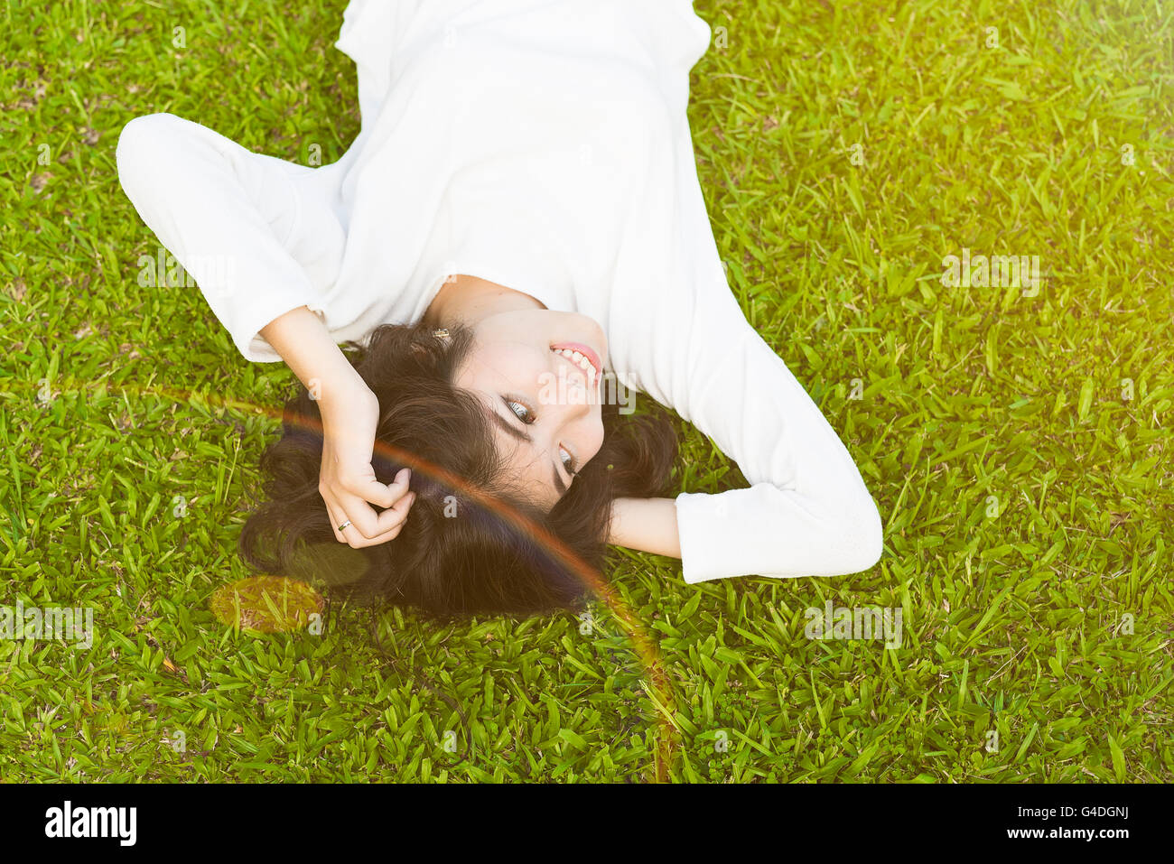 junge Asiatin liegen auf dem Rasen Stockfoto