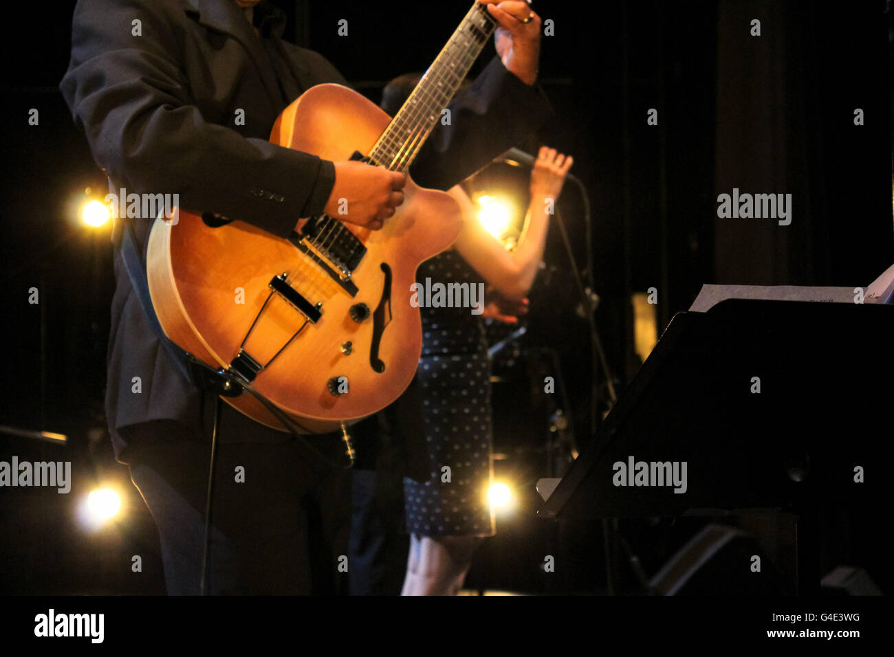 Foto von einem Musiker, spielt seine Gitarre und eine Frau singt Stockfoto