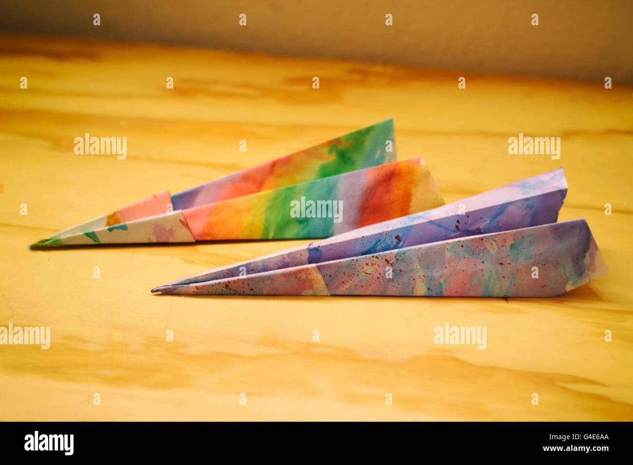 Foto von einige bunte Papierflieger auf einem Holztisch Stockfoto