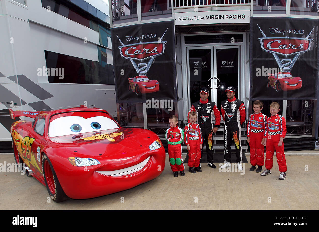 Die Virgin Racing-Fahrer Timo Glock und Jerome d'Ambrosio posieren während des Paddock-Tages für einen Disney Pixar Cars 2 Fotocall für den Formel 1 Santander British Grand Prix auf dem Silverstone Circuit, Northampton. Stockfoto