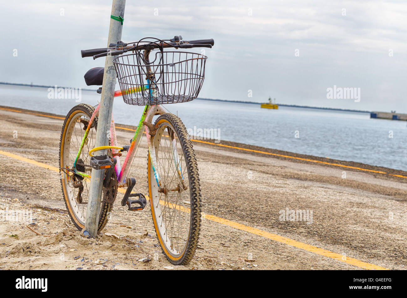 alte rostige Fahrrad angekettet an einem Pol auf dem pier Stockfoto