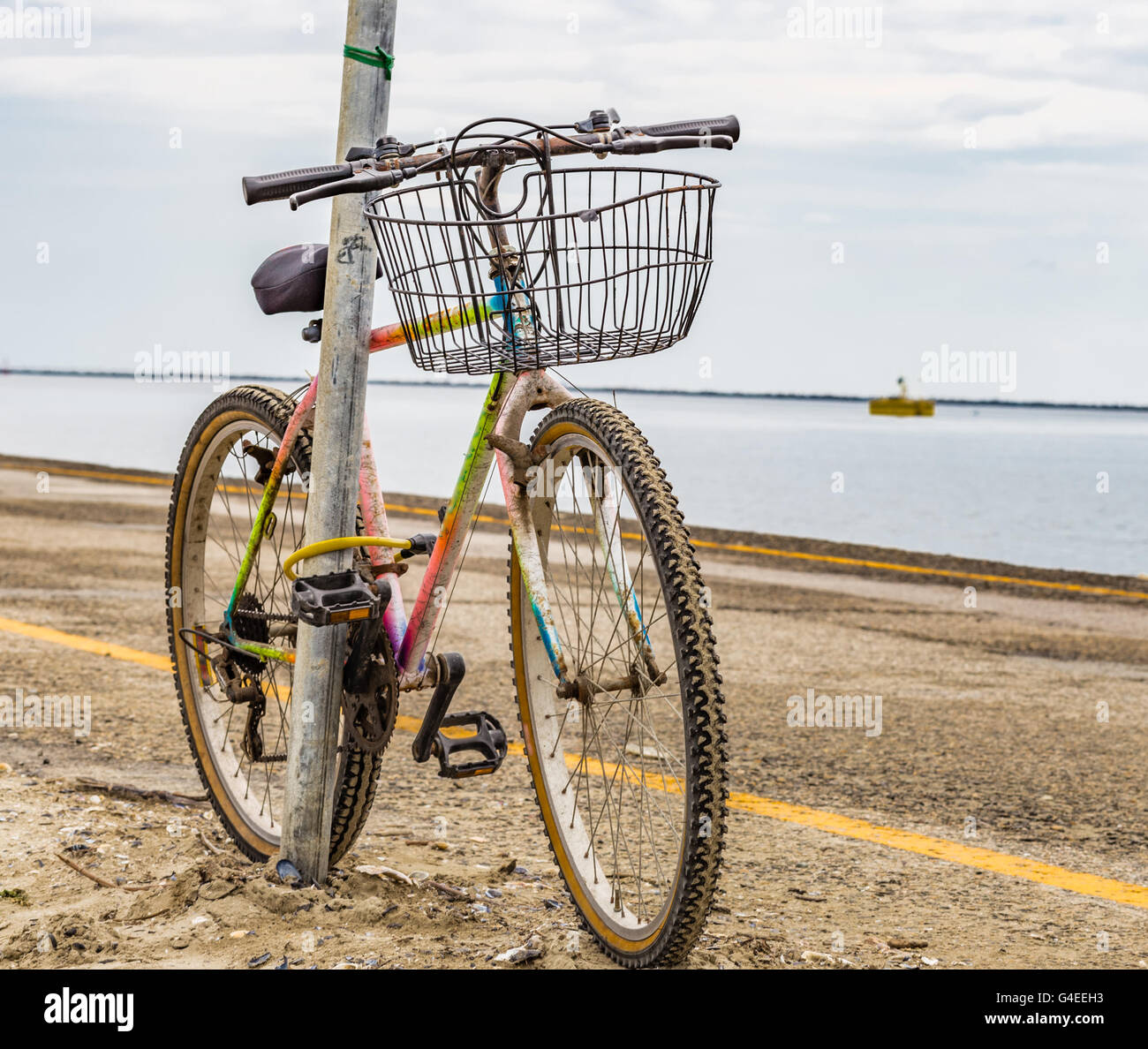 alte rostige Fahrrad angekettet an einem Pol auf dem pier Stockfoto