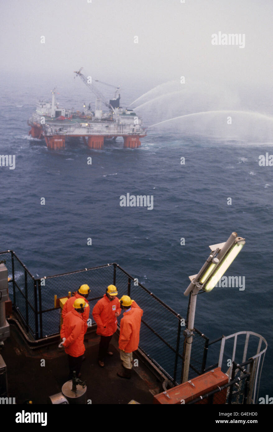 Der Prinz von Wales (extreme Rechte) im Gespräch auf der BP Forties Bravo Plattform in der Nordsee. In der Ferne testet das Rettungsschiff „Iolair“ seine Schläuche. Stockfoto