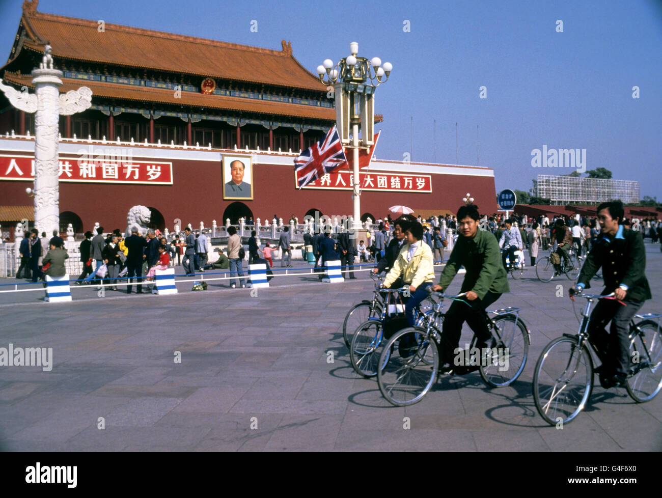 Radfahrer passieren die Verbotene Stadt in Peking mit einem Porträt des Vorsitzenden Mao und der Gewerkschaft Jack draußen. Stockfoto